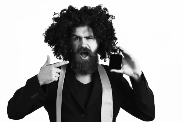 Caucasian hipster in suit and black curly wig holding perfume — Stock Photo, Image