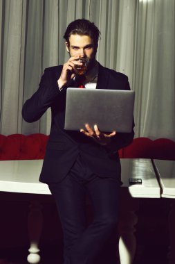 Sakallı adam, bir bardak viski, cep telefonu, dizüstü bilgisayarı olan iş adamı.