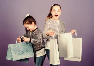 Alışveriş günü. Çocuk paketleri. Çocuk modası. Kız kardeş kız arkadaş, alışveriş torbaları, mor arka plan. Çünkü imaj her şeydir. Alışveriş ve satın alma. Kara Cuma. Satış ve indirim.