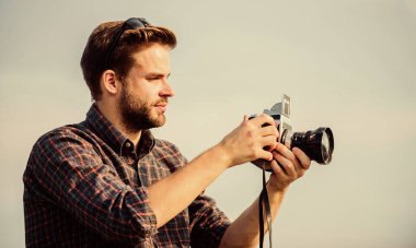 Adam açık havada gökyüzü arka planında. Antika ekipmanlar. Blogger video blogu çekiyor. Tatil zamanı. Yakışıklı blogcu, gezgin, geçmişe dönük kamera. Fotomuhabir konsepti. Gezgin blogcu. Gazeteci fotoğraf çekiyor.