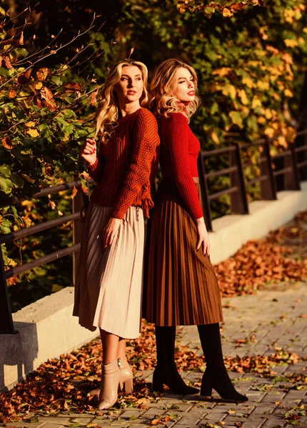 Colorful fall forest. real femininity. autumn women outdoor. girl friends walk in park. sunny day with leaves. fall fashion season. Pleated trend. girls in corrugated skirt and sweater. female beauty — Stock Photo, Image