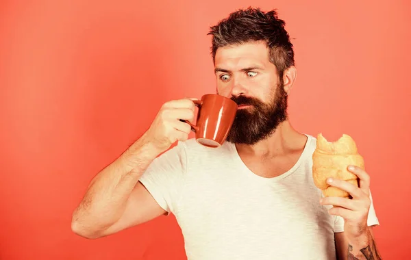 Baard hipster genieten van ontbijt drinken koffie. Ochtendtraditie concept. Ongezond, maar lekker ontbijt. Verse gebakken croissant. Heerlijk ontbijt. Man start ochtend met koffie en croissant — Stockfoto