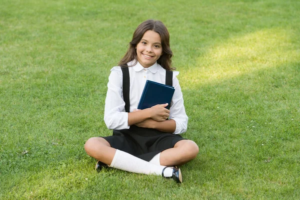 Дівчина-підліток з книгою на зеленій траві. гарна маленька дівчинка читає книжку. вивчати літературу для дітей. розважатися з книжкою. День знань. сучасна шкільна освіта. щасливе дитинство — стокове фото
