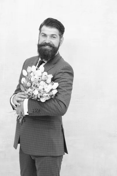 Womens day. March 8. Spring gift. Bearded man hipster with flowers. Celebrate spring. Making surprise. Gentleman with tulips. Spring is coming. Greetings. Bearded man with tulip bouquet. Love date