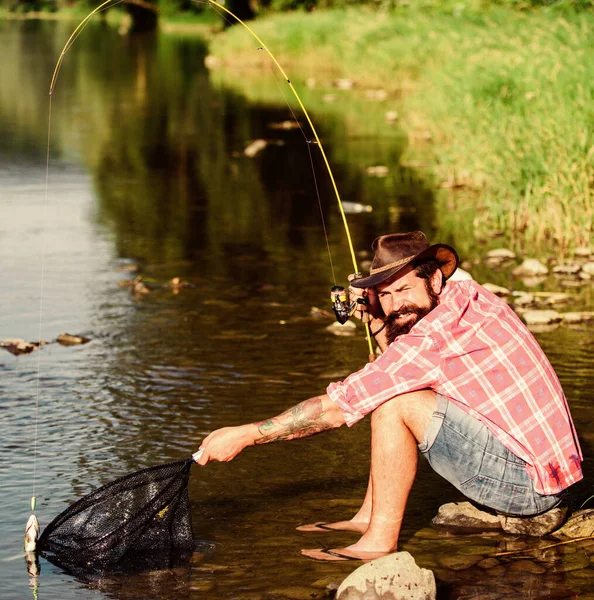 Desechando a ese pez. hombre con pescado en caña. pesca de caza mayor. relajarse en la naturaleza. pescador exitoso en el agua del lago. pesca hipster con cuchara-cebo. pez mosca hobby del hombre. Hipster en camisa a cuadros —  Fotos de Stock