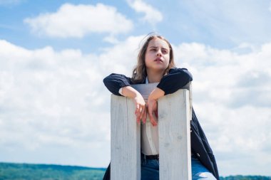 Müthiş bir güzellik. Rahatlama zamanı. Güzellik ve yaz modası. Gökyüzü arka planındaki neşeli çocuk. Modayı takip eden bir çocuk. Mutlu çocukluk. Küçük kızın uzun gür saçları var. Çocuk sandalyeye otur.