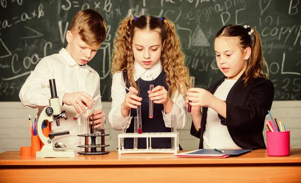 Educación formal. Laboratorio escolar. Los alumnos de la escuela grupal estudian líquidos químicos. Las niñas y los niños estudiantes realizan experimentos escolares con líquidos. Lección de química escolar. Tubos de ensayo con sustancias —  Fotos de Stock