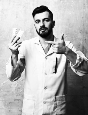 Doktor sakallı ve yüz ifadesi kesin hapları gösteriyor.