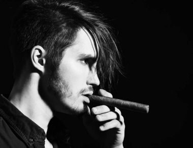 Ciddi sakallı adam puro içiyor.