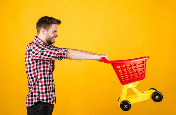 Weekend on buying products. rejoices successful purchases. spends money unwisely. customer pushing cart. buyer in supermarket. empty toy trolley. man go shopping. funny man with small shopping cart — Stock Photo, Image