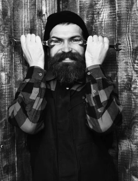 Bearded brutal caucasian mechanic holding metallic wrenches — Stock Photo, Image