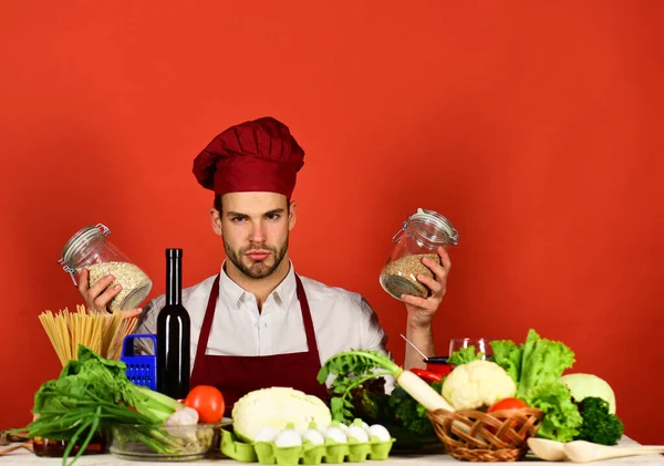 Vegetarian meal concept. Chef with serious face holds porrige jars — Stock Photo, Image