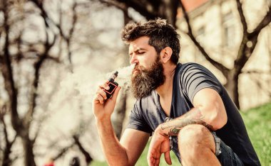 Sakallı adam duman üfledi. Kokulu duman bulutları. Stres atma konsepti. Tüttüren sakallı adam. Elektronik sigara içiyorum. Sigara içme cihazı. Uzun sakallı adam sigara içmekten rahatlamış.