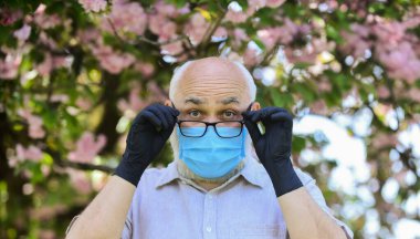 Yaşlandıkça bağışıklık sistemi enfeksiyonlarla mücadelede daha az etkili oluyor. Dışarıda maskeli ve eldivenli kıdemli bir adam var. Yaşlılara nasıl yardım edileceğini. Özellikle yaşlılar enfeksiyon kaptıysa risk altındalar.