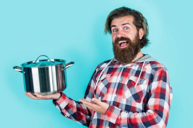 Ürün sunumu. Adam yeni marka tavayı tutuyor. Mutfak gereçleri. Mutfakta erkeklerin ellerinde demlik pişiriyorum. Yemek hazırlamak ve yemek pişirmek. Mutfak aletleri. Mutfak reklamı. Tencereli adam.