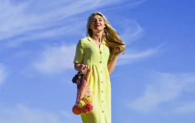 Sıfır kayıp. Plastiksiz konsept. Alışveriş için tekrar kullanılabilir pamuk ve ağlı eko poşetler. Kız yaz günü mavi gökyüzü arka planı. Çevreye duyarlı. Kadın eko torbasında meyve ve sebze taşıyor. Sürdürülebilir yaşam tarzı