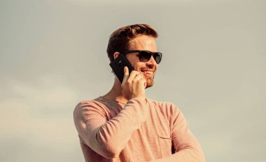 Davaları telefonla çözmek. Sıradan bir adam. Moda modeli. Seksi erkek gökyüzü arka planı. Maço adam cep telefonu kullanıyor. Hayattaki modern teknoloji. Her zaman görüşüyoruz. Kendine güvenen bir adam telefonda konuşur. Arkadaşına seslen
