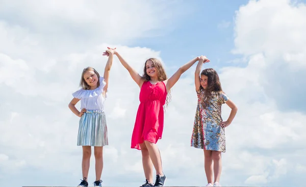 Vi är starka. Systerskap och vänskap. Dags för familjeband. bästa vänner för alltid. tre systrar på himlen bakgrund. Lycklig barndom. sommarsemester. Små flickor håller varandra i handen. kärlek och stöd — Stockfoto