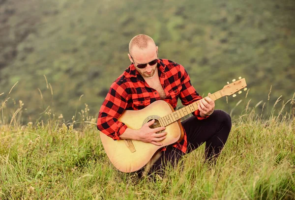 Man with guitar on top of mountain. Acoustic music. Music for soul. Playing music. Sound of freedom. Musician hiker find inspiration in mountains. In unison with nature. Keep calm and play guitar
