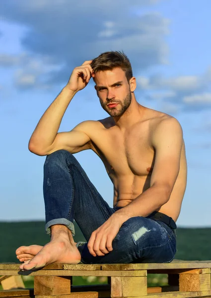 Modelo de fitness. Atlético guapo macho usar pantalones de mezclilla. Cuerpo muscular. Torso desnudo muscular. Seis paquetes de pecho musculoso. Hombre al aire libre cielo azul de fondo. Concepto de belleza masculino. Lookbook de verano —  Fotos de Stock