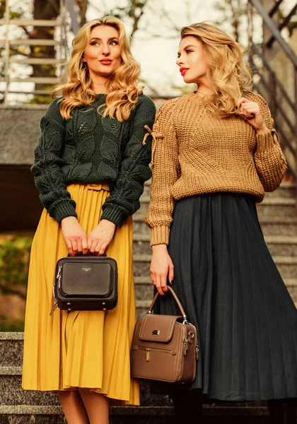 Matching colors. Personal stylist service. Sweater skirt trend. Completing each other. Vogue concept. Girls blonde wear matching clothes. Matching outfits. Women sisters outdoors stairs background