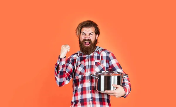 Just for fun. Enameled cast iron cooking vessels. Nonstick pan coated polytetrafluoroethylene teflon. Cooking healthy food. Professional chef man cook in checkered shirt. bearded husband. Restaurant