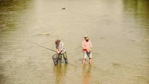 Fim de semana. Pescador feliz com vara de pesca e rede. Atividades hoteleiras e desportivas. A pescar juntos. Ensina o homem a pescar e alimenta-lo para sempre. Amizade masculina. Pai e filho pesca — Fotografia de Stock