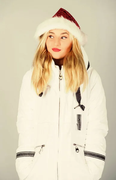 Mikulás lány. A lány fehér kabátot és télapó sapkát visel. A kabát extra szigeteléssel rendelkezik, és kissé hosszabb ideig alkalmas arra, hogy megvédje a testét az éles téli időjárástól. Fehér dzseki. Várakozó fagyos karácsonyi napok — Stock Fotó