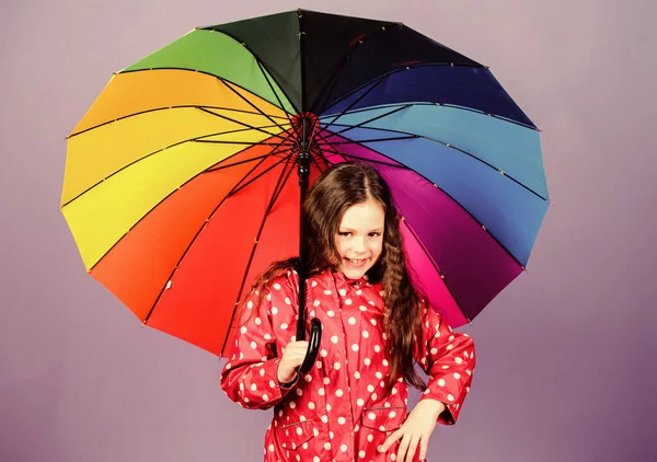Rainy day fun. Happy walk under umbrella. Enjoy rain concept. Fall season. Kid girl happy hold colorful rainbow umbrella. There is rainbow always after the rain. Rainy weather with proper garments — Stock Photo, Image