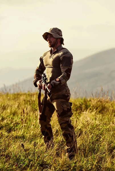 Fuerzas del ejército. Ropa militar de hombre con arma. Guerrero brutal.  Rifle para cazar. Listos para disparar. Cazador de rifle. Hunter montañas  paisaje fondo. Enfoque y concentración cazador experimentado: fotografía de  stock ©