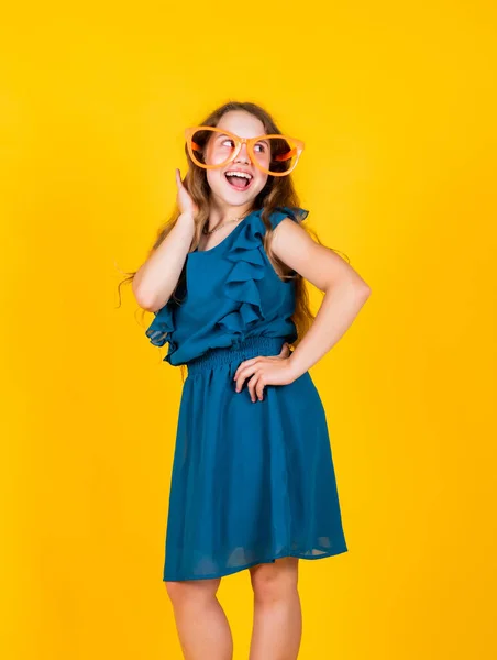 Αστεία γυαλιά για πάρτι. Κομμωτήριο ομορφιάς. Παιδική ευτυχία. Μικρό μοντέλο μόδας. Ένα μικρό κορίτσι φοράει φόρεμα. Παιδί με χαρούμενο χαμόγελο. τέλεια κομψή εμφάνιση. παιδική ομορφιά και μόδα — Φωτογραφία Αρχείου