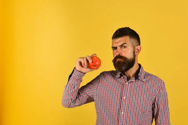 Άντρας με γενειάδα κρατά κόκκινο μήλο απομονωμένο σε κίτρινο φόντο — Φωτογραφία Αρχείου