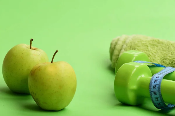 Haltères de couleur vert vif, ruban à mesurer, serviette et fruits — Photo