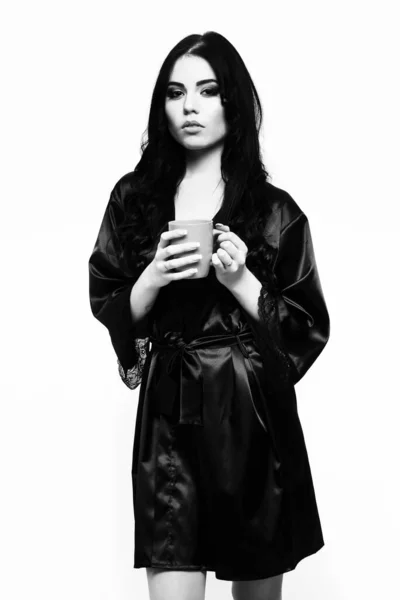 Сексуальная девушка позирует в черном шелковом халате с чашкой — стоковое фото