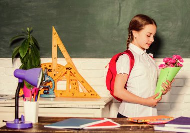 Bilgi Günü 'nü tebrik ederim. 1 Eylül. Okula dönelim. Sırt çantalı sevimli kız öğrenci öğretmen için çiçek taşıyor. Okul tatili. Minnettar okul kızı. Okul pedagogu için selamlar.