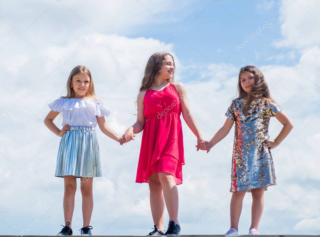 love and support. concept of sisterhood and friendship. family bonding time. best friends forever. three sisters on sky background. happy childhood concept. summer vacation. small girls hold hands