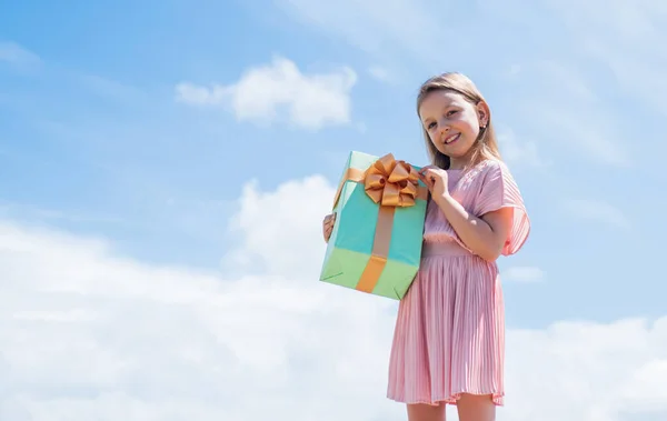 Ragazzino con confezione regalo. Buona festa di compleanno. felicità infantile. festeggiamo la vacanza. bambino in giorno d'estate su sfondo cielo. il suo tempo di shopping. piccola ragazza tenere scatola regalo. copia spazio — Foto Stock