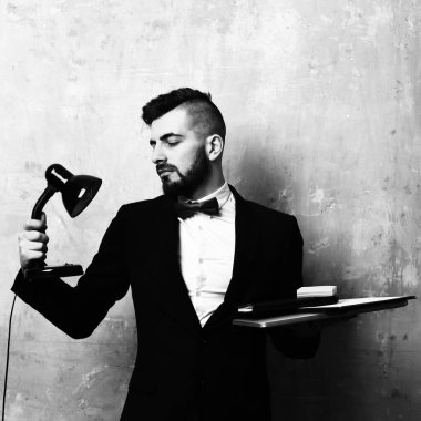 Düzgün sakallı ve mutlu yüz ifadesi olan komisyoncu lamba tutar.