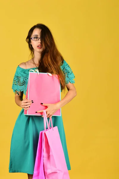 Lady fica no fundo amarelo, segura sacos de compras rosa . — Fotografia de Stock