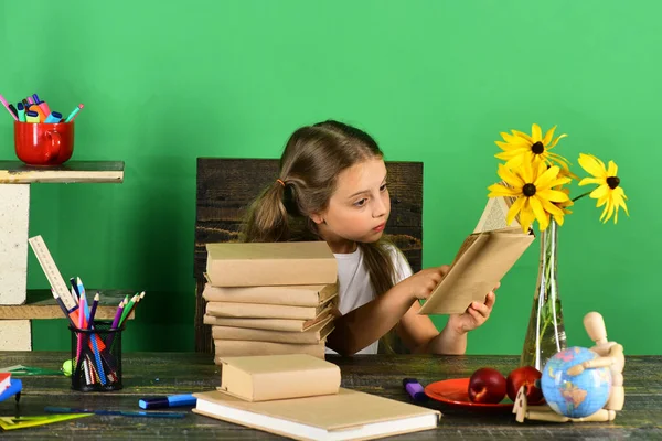 Estudante senta-se na mesa com artigos de papelaria coloridos, livros e flores — Fotografia de Stock