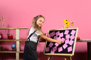 Sınıfında kitap raflarıyla gülümseyen kız öğrenci.