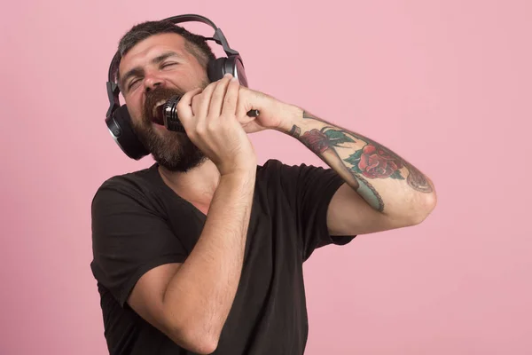 Dj con barba usa auriculares. El hombre canta sobre fondo rosa , — Foto de Stock