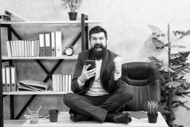 İnternette rahatla. Kişisel bakım. Rahatlama teknikleri. Zihinsel refah ve rahatlama. Adam sakallı yönetici resmi takım elbise lotus pozu rahatlatıcı. Uygulama akıllı telefonu. Oyun oynayın. Haberler iyi. Sosyal ağlar