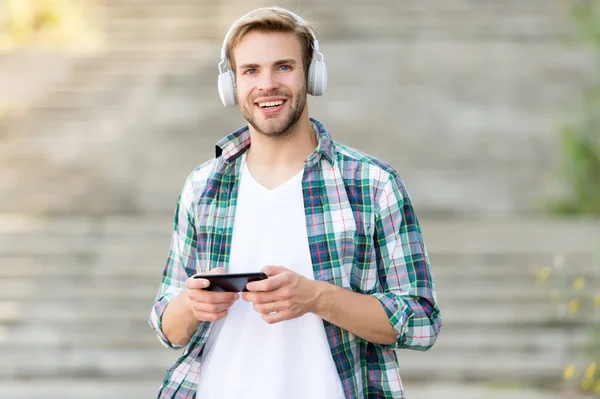 Spojte se s technologií. Šťastný muž hraje hudbu v chytrém telefonu. Fešák nosí sluchátka. Nová technologie. Mobilní technologie. Moderní život. Vynikající technologie pouze pro vaše uši — Stock fotografie