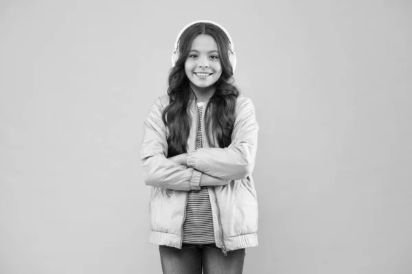 smiling schoolgirl. Enjoying song playing in headphones. Karaoke party fun. Fun and entertainment. Joining in a song. Small girl with sad look pink background. Little child hear stereo sound