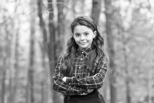 Mode trend. Accessoires. Mooie kinder natuur achtergrond. Gewatteerde hoofdband. Een lachend meisje draagt een geknoopte hoofdband. Grootste haaraccessoire trends. Schattig klein meisje geruite shirt dragen rode hoofdband — Stockfoto