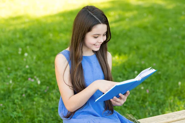 Leia e veja o que grandes coisas estão no livro. Menina feliz ler livro no banco do parque. Pequeno leitor no verão ao ar livre. Leia para se divertir. Fantasia e ficção. Literatura e poesia. Nascido para ler — Fotografia de Stock