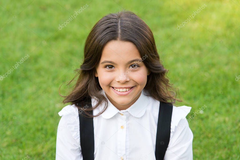 she is so cute. happy childhood. back to school. Small girl wear school uniform. beauty and fashion. beautiful student teen girl in park. cute smiling confident schoolgirl relax on green grass