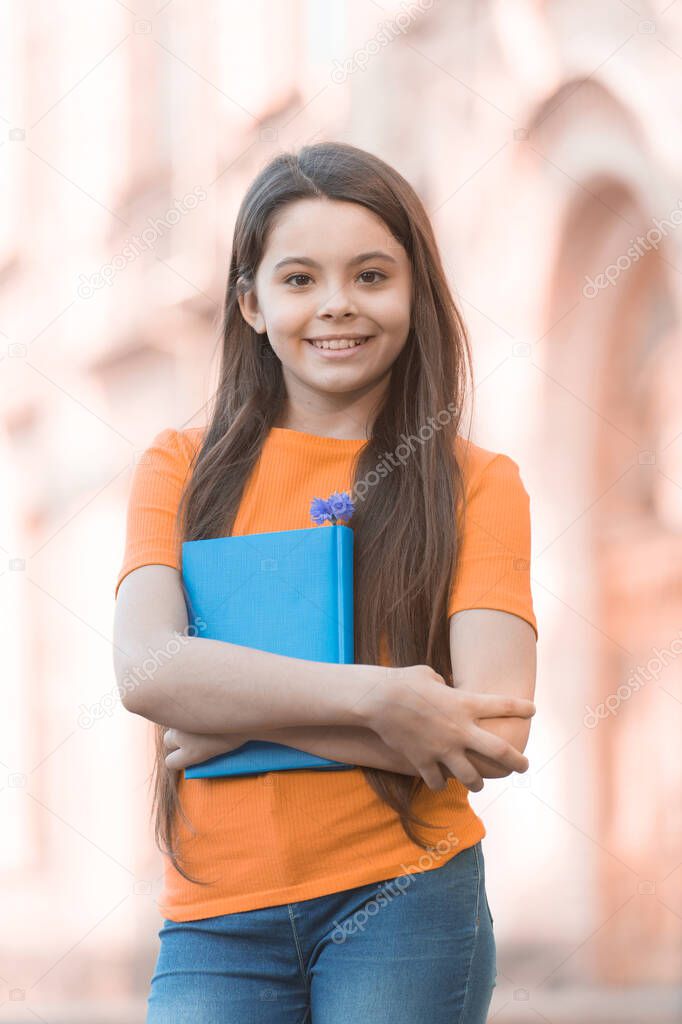 For creative learning. Happy schoolgirl outdoors. Little schoolgirl back to school. Small schoolgirl hold book. Fashion look of cute schoolgirl. Casual style. School and education. School library