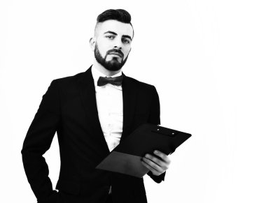 Sakallı şık bir sunucu ve klasik takım elbiseli şık bir saç modeli.